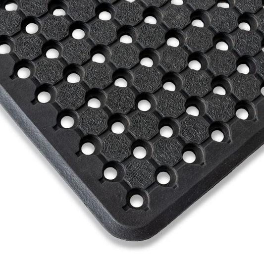 Close-up view of a black rubber utility mat with a pattern of circular holes designed for drainage.