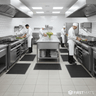 Commercial kitchen with chefs working at stainless steel counters and ovens, while standing on rubber mats.