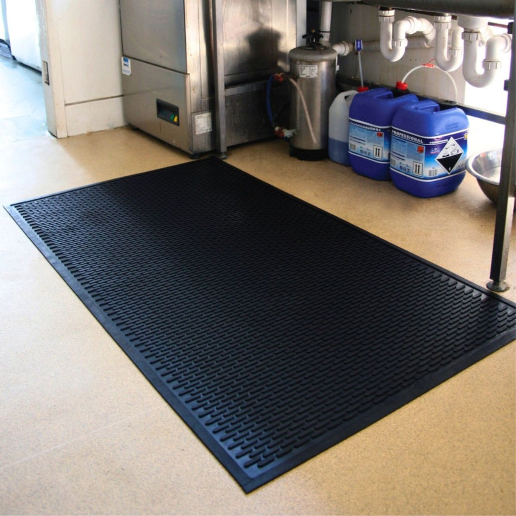 Black mat on a kitchen floor with appliances and cleaning supplies in the background