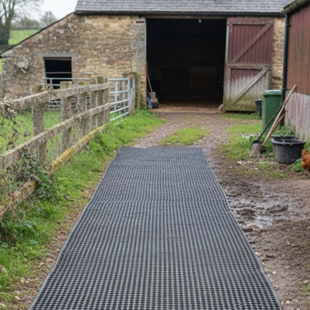 Long black rubber mat leading to a barn with open doors.