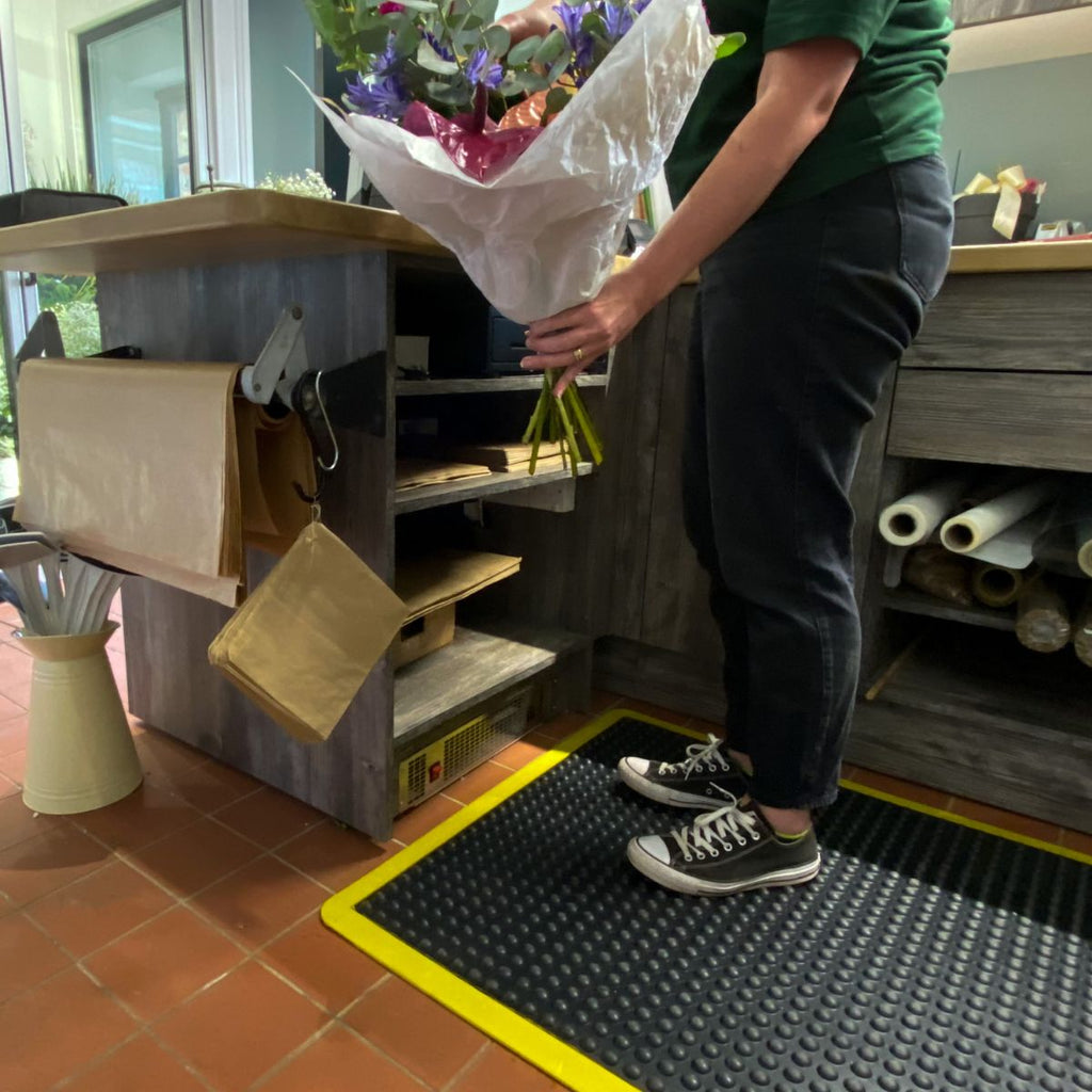 Person holding a bouquet of flowers in an indoor setting with shelves and tools.