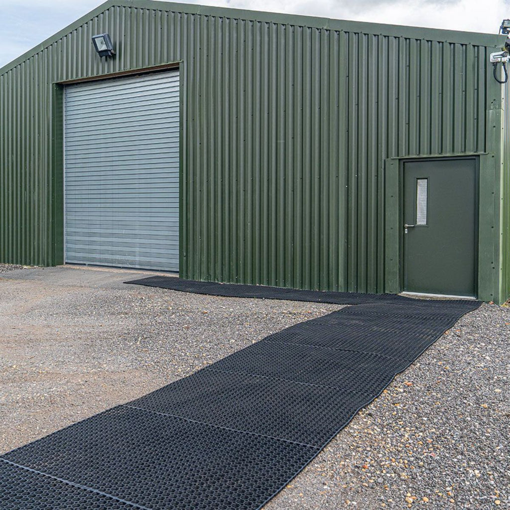 Green metal building with a black mat on the ground in front