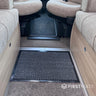 Car interior with a black textured mat on the floor, surrounded by beige seats.