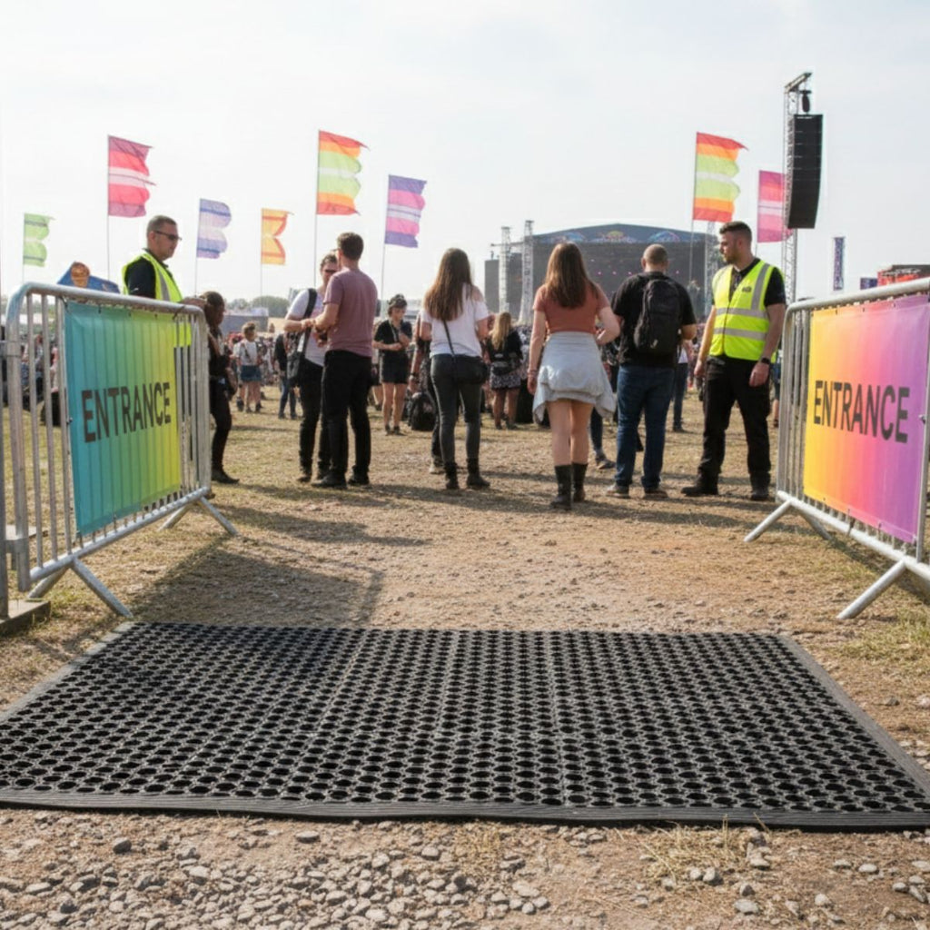 People entering a festival through rainbow-colored flags and barriers.