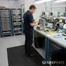 Person standing on an ESD mat in a laboratory with electronic equipment on a table.