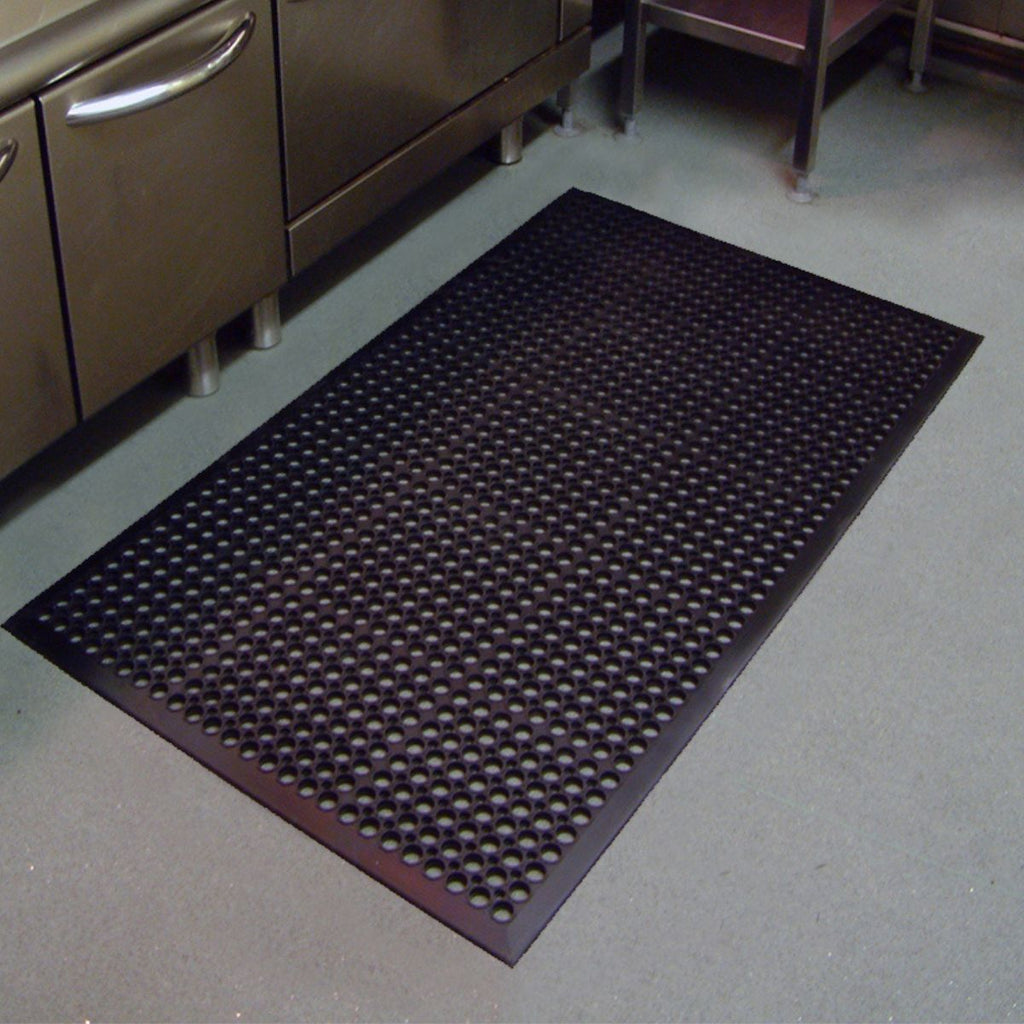 Black anti-fatigue mat on a gray floor in a kitchen setting