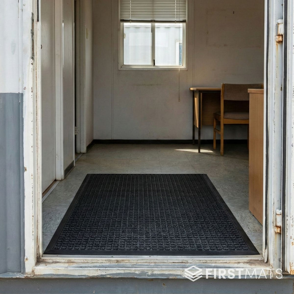 Black mat on a portacabin floor with a door open to an indoor setting.