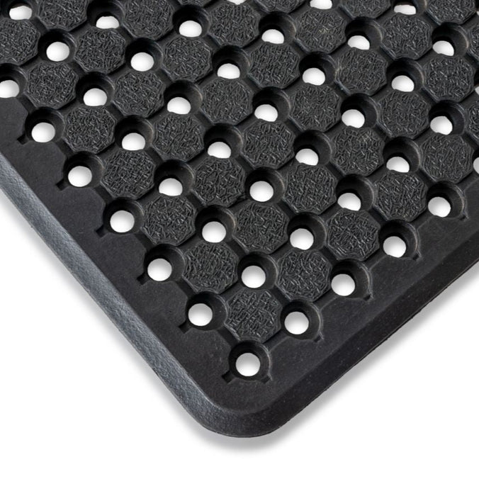 Close-up view of a black rubber utility mat with a pattern of circular holes designed for drainage.