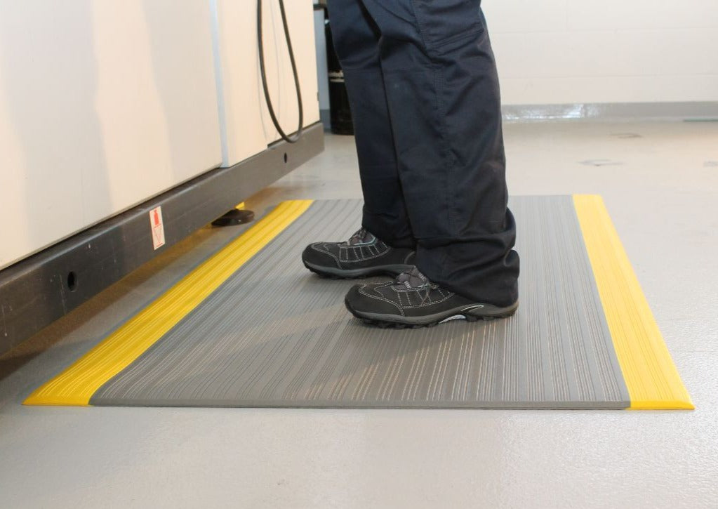 Grey and yellow AtEase anti-fatigue industrial mat for comfort on hard floors.